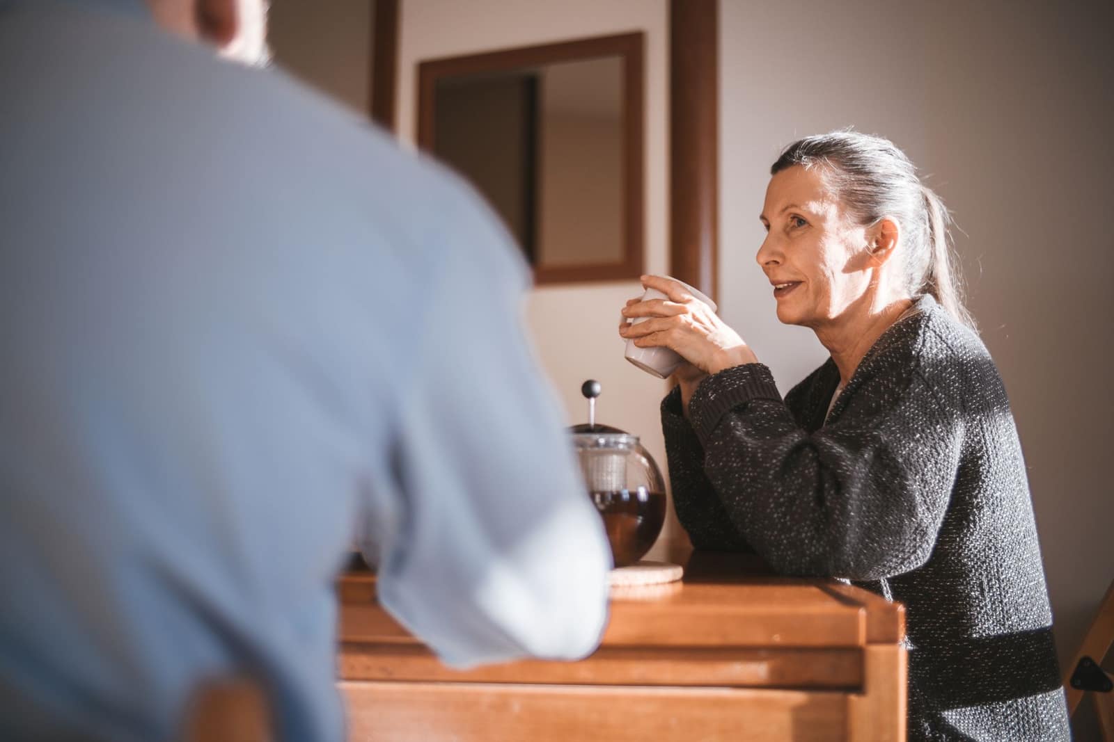 An older adult chats warmly over coffee at home while everyday appointments and errands are quietly coordinated on their behalf.